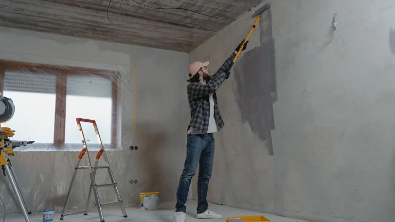 Muncitor care zugrăvește un perete în timpul renovării