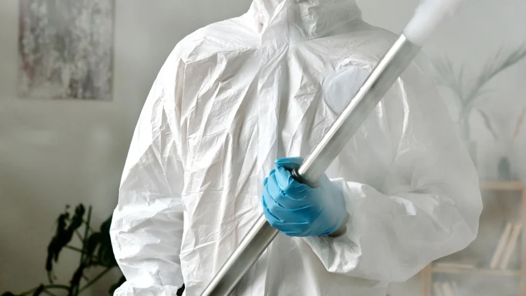 Tehnician în costum de protecție care face dezinfecție